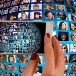 A smartphone is taking a picture of a globe of people found on social media.