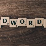Scrabble tiles spelling out the word 'ADWORDS' on a wooden surface.